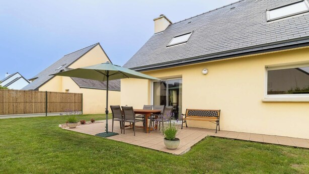 A residential house with a patio, a table with chairs, a bench, and a covered outdoor seating area. - Large family house in Fréhel | 8 guests | Ref 300 (FREHEL)