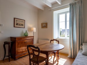 Un coin repas avec une table et des chaises en bois, un vase vert et deux tableaux encadrés accrochés au mur.