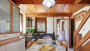 Un comedor con una mesa dispuesta para dos, techo de madera y chimenea de piedra.