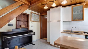 Una cocina con vigas de madera, un piano y un lavamanos.