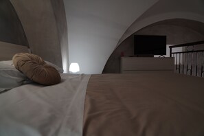 Une chambre à coucher avec un lit, un téléviseur posé sur une commode et une fenêtre.