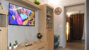 A modern living room with a flat-screen TV, wooden entertainment unit, and a glass cabinet.