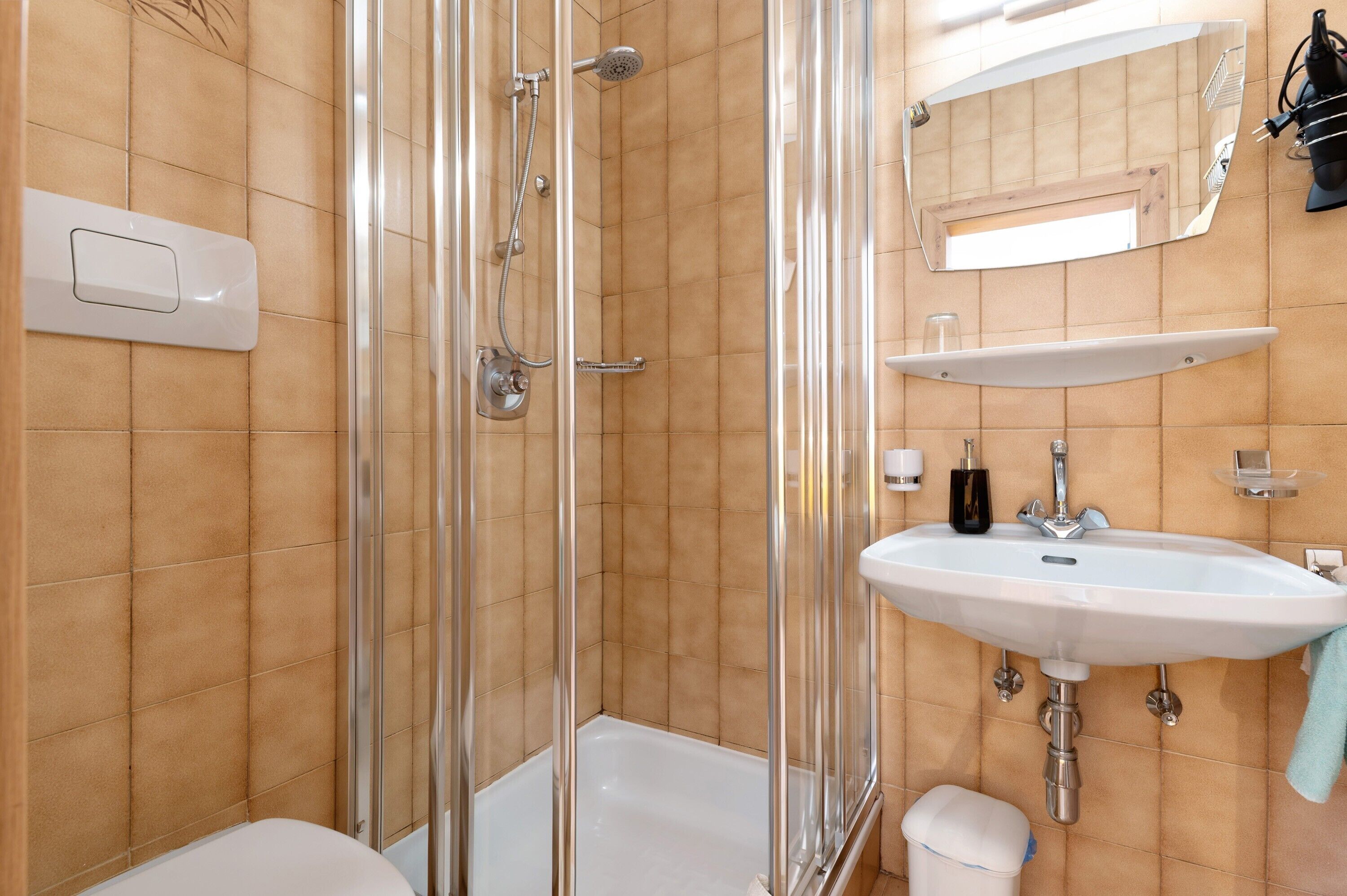Une salle de bain avec une douche à parois de verre, un lavabo blanc et un miroir au-dessus du lavabo.