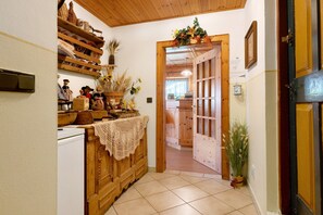 Un couloir avec des meubles de rangement en bois, un réfrigérateur blanc et une porte donnant sur une autre pièce.