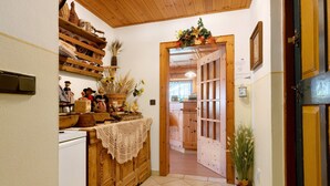 A hallway with wooden cabinets, a white refrigerator, and a door leading to another room. - Room 'Veltierhof 6' with Mountain View, Private Terrace and Wi-Fi (Funes)