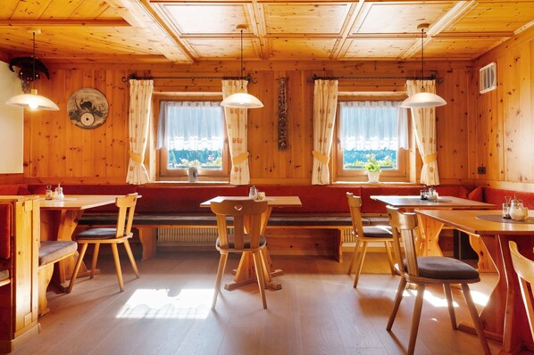 A wooden interior with a dining area, benches, and tables.