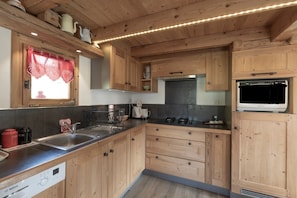 A compact kitchen with wooden cabinets, a Bosch dishwasher, a stove, and a built-in oven. - Chalet 'Bel Andain' with Mountain View, Private Terrace and Private Garden (Hauteluce)
