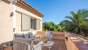 An outdoor patio with a sofa, chairs, a table with fruit, and a sign reading 'MAISON DE FAMILLE'. - Villa 'Chantegrive' with sea view, Wi-Fi and air conditioning (Roquebrune-sur-Argens)
