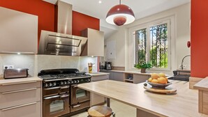 A modern kitchen with stainless steel appliances, a wooden island, and a large window. - Villa 'Chantegrive' with sea view, Wi-Fi and air conditioning (Roquebrune-sur-Argens)