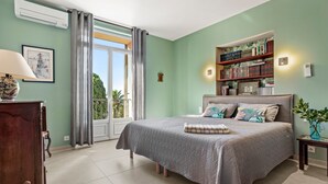 A bedroom with a bed, a bedside table, a lamp, a bookshelf, and a window with curtains. - Villa 'Chantegrive' with sea view, Wi-Fi and air conditioning (Roquebrune-sur-Argens)