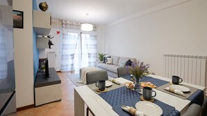 Ein modernes Wohnzimmer mit Essbereich, einer Couch, einem Couchtisch und einem Fernseher.