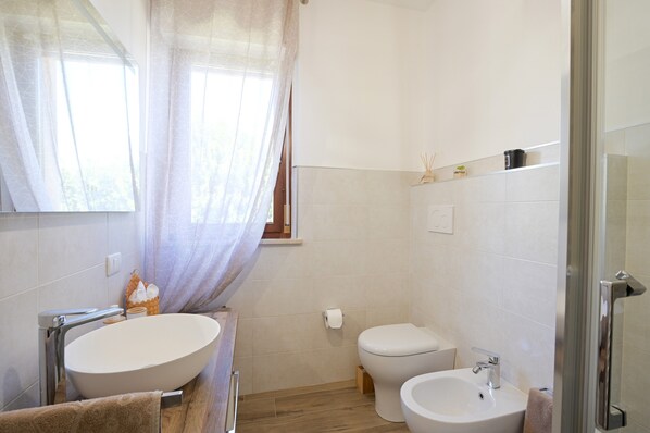 Un baño con un lavamanos ovalado grande, inodoro y zona de ducha.