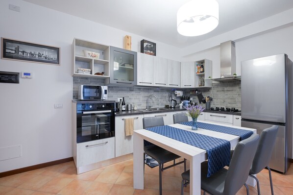A modern kitchen with white cabinets, a built-in oven, microwave, and stainless steel refrigerator.