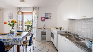 A kitchen with white cabinets, a tiled backsplash, and a dining area with a table and chairs.