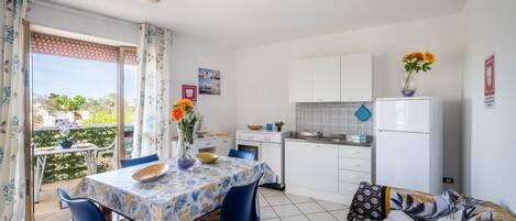 A compact living space with a dining area, kitchenette, and a balcony with a view.