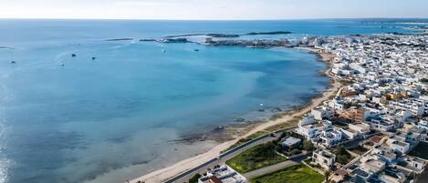Vista aérea de un pueblo costero con playa, edificios y barcos.