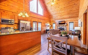 Un intérieur spacieux de chalet en bois, comprenant une cuisine, un coin repas et un salon.