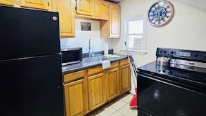 A kitchen with wooden cabinets, a black refrigerator, a microwave, a sink, and a stove.