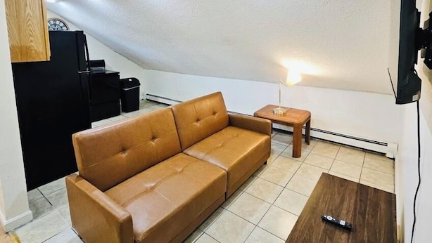 A modern living room with a brown leather sofa, a wooden coffee table, and a television mounted on the wall.