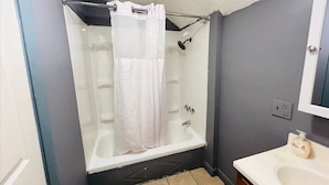 A bathroom with a shower, a bathtub, a sink, and a mirror.