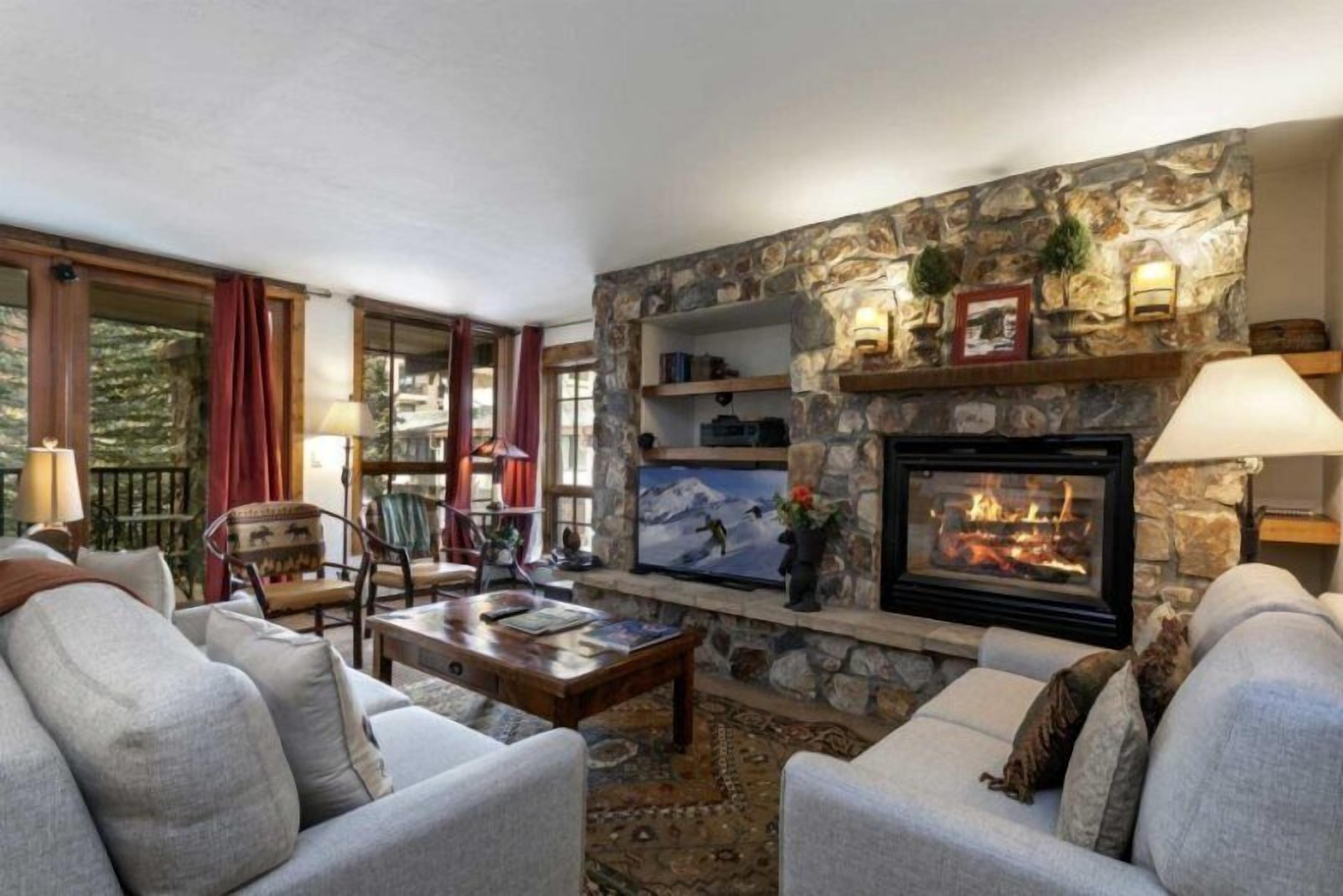 Una sala de estar acogedora con chimenea de piedra, asientos cómodos y un televisor.