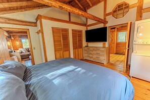 A bedroom with a large bed, wooden walls, a television, and a washing machine.