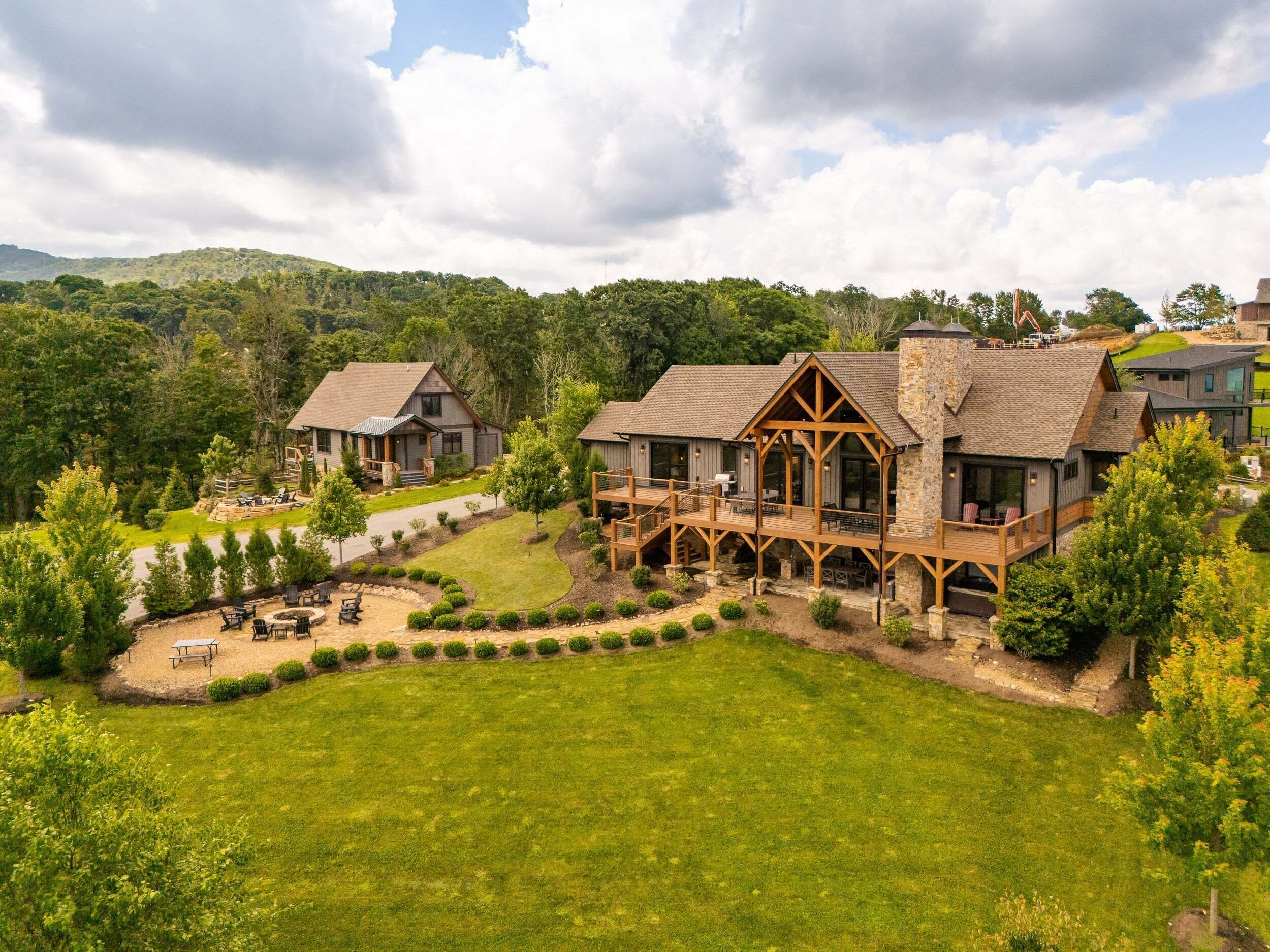A large, multi-story lodge with a spacious deck and outdoor seating area.