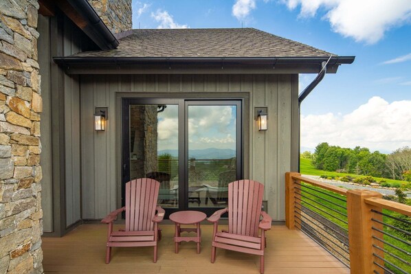 A deck with two chairs and a table, overlooking a scenic landscape.