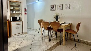A compact dining area with a wooden table, four wicker chairs, a microwave, and a cabinet with dishes. - Cozy 2-bedroom apartment in beautiful Yauco with AC, WiFi (Yauco)