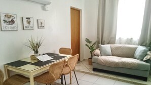 A dining area with a table and chairs, a sofa, and a potted plant. - Cozy 2-bedroom apartment in beautiful Yauco with AC, WiFi (Yauco)