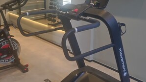 A home gym with a treadmill, weights, and a TV mounted on the wall. - Charming studio next to PUC-SP, Allianz Parque and Pacaembu (Perdizes São Paulo)