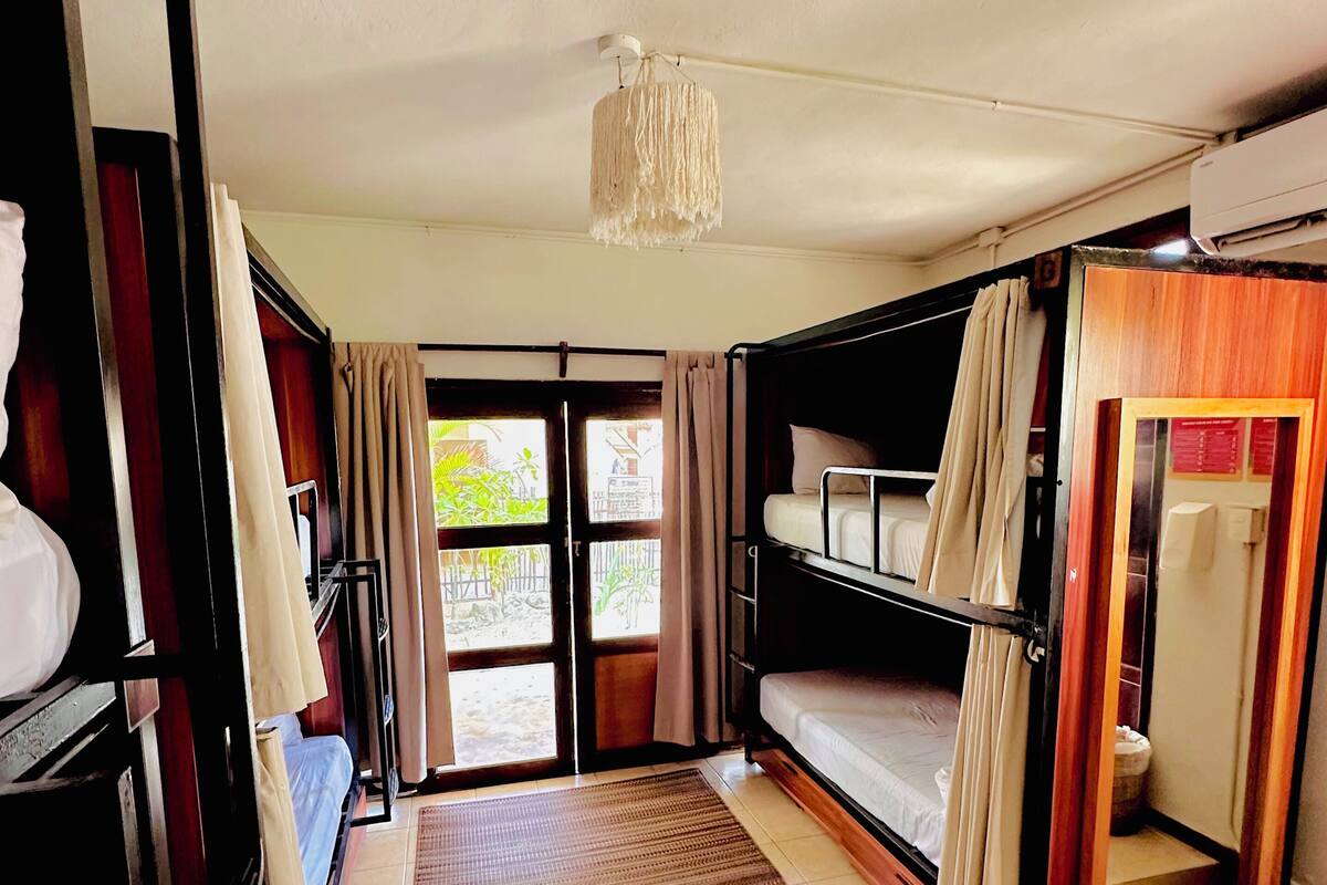 A room with bunk beds, a hanging light fixture, and a view of the outside.