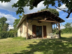Guesthouse with a rustic charm, surrounded by a well-maintained lawn and shaded by trees.