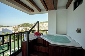 Een balkon met een jacuzzi, uitzicht op een stadsbeeld en een trap.