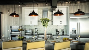 A modern kitchen with stainless steel appliances, a central island with seating, pendant lighting, and a decorative vase with greenery. - First Class Penthouse 3 bed 3 bath + Dipping Pool - CPH2 (Puerto Vallarta)