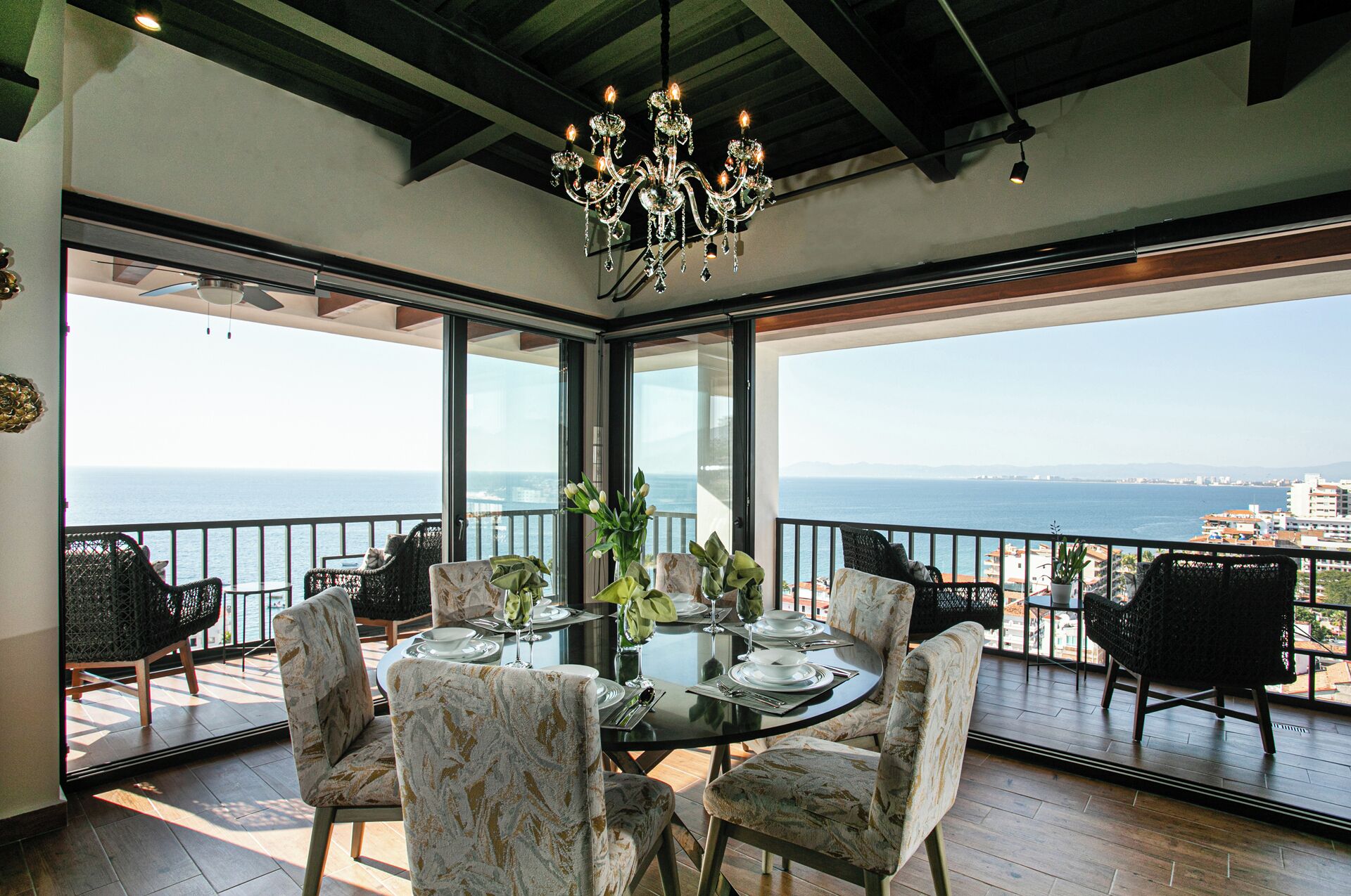 Comedor con una mesa dispuesta para cuatro personas, rodeado de sillas y vistas panorámicas al océano.