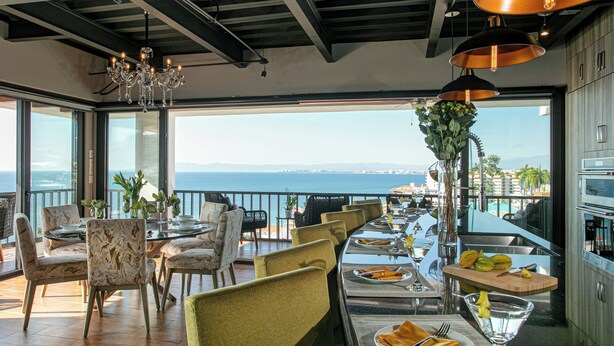 A dining area with a view of the sea, featuring a long table set for dining, chairs, and a chandelier. - First Class Penthouse 3 bed 3 bath + Dipping Pool - CPH2 (Puerto Vallarta)