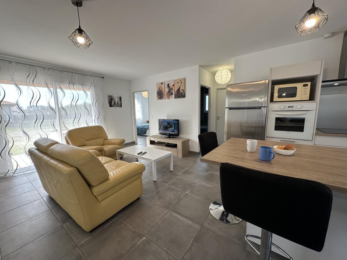 Ein modernes Wohnzimmer mit Sofa, Couchtisch, Fernseher und einer Essecke mit Tisch und Stühlen.