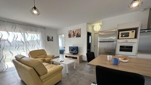Ein modernes Wohnzimmer mit Sofa, Couchtisch, Fernseher und einer Essecke mit Tisch und Stühlen.