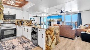 A modern kitchen with white cabinets, stainless steel appliances, and a marble island. - 1002 Oceanfront Pelican Beach Resort Amazing Location Multiple Pools & Hot Tubs (Destin)