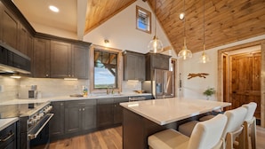 A modern kitchen with dark wood cabinets, stainless steel appliances, and a large island with bar stools.