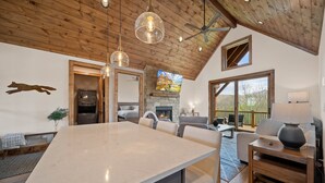 A spacious living area with a large marble island, wooden ceiling, and a fireplace.