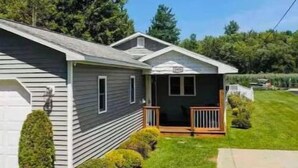 A single-story mobile home with a front porch, a garage, and a well-maintained lawn.