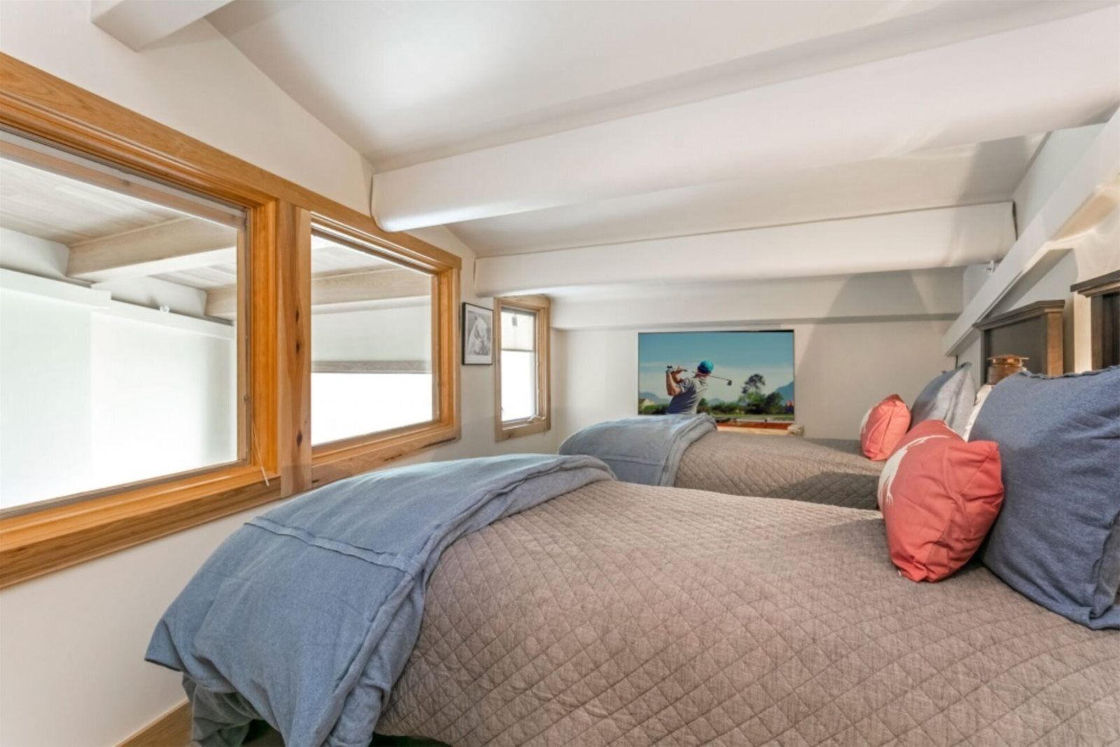 Ein Schlafzimmer mit zwei Betten, einem großen Fenster und einem Gemälde an der Wand.