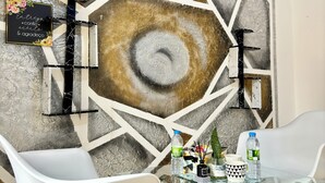 A modern room with a geometric wall design, a glass table with chairs, and a sign with a message. - Charming 1BR Apt in the Heart of Maculusso-Free Netflix-High speed wifi (Luanda)