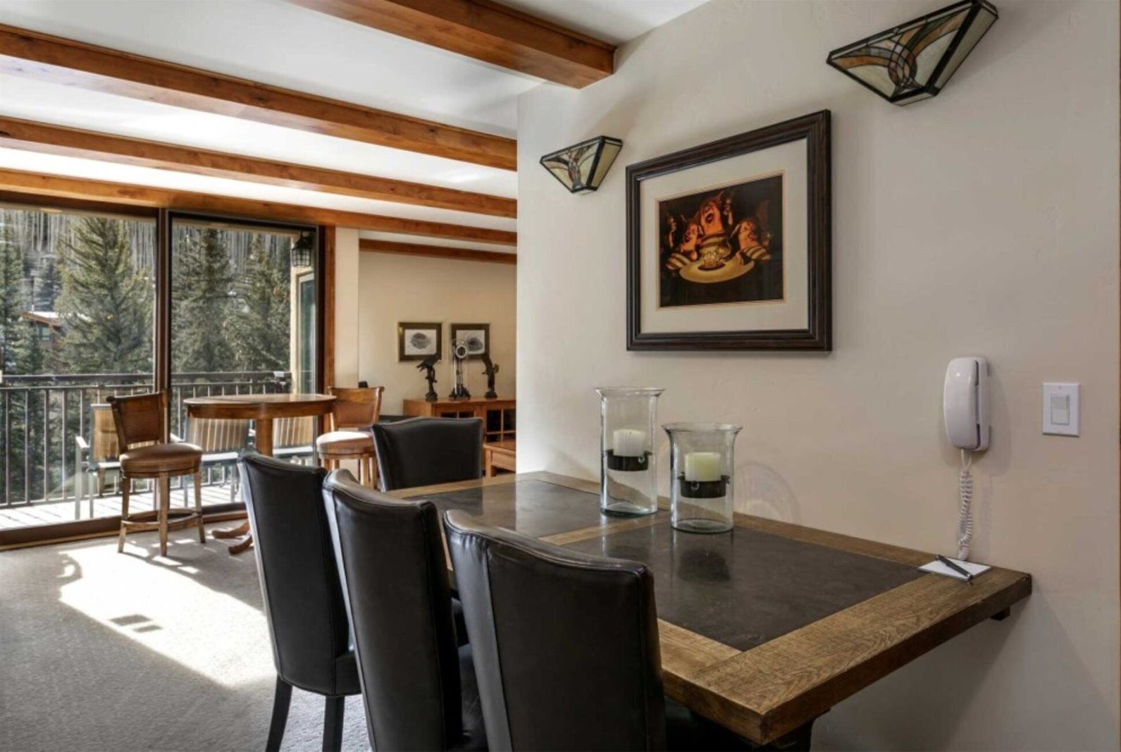 A dining area with a wooden table, black chairs, and a framed picture on the wall.