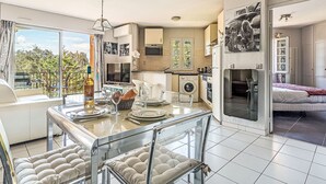 A modern kitchen with a dining area, a washing machine, and a bed in the adjacent room. - Le Clos Sainte Anne by Interhome (Saint-Tropez)