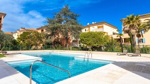 A swimming pool with a metal ladder, surrounded by a tiled deck. - Le Clos Sainte Anne by Interhome (Saint-Tropez)