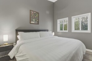A bedroom with a bed, a nightstand, a lamp, and a framed botanical illustration on the wall.
