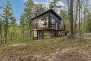 A cabin with a deck, surrounded by trees.
